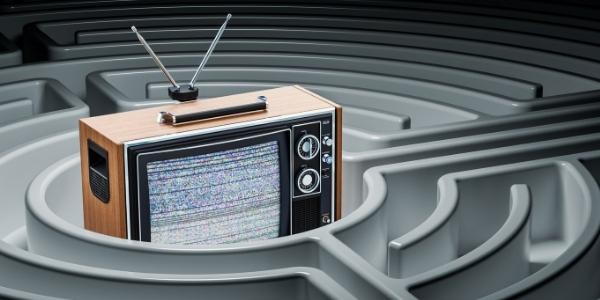 "Stara televizija z motnjo signala stoji v središču labirinta – metafora za kompleksnost, ki jo razkriva vodnik za tv oglaševanje.