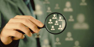 Targeting – povečevalno steklo usmerjeno na skupino ljudi, simbolizira ciljno usmerjanje.